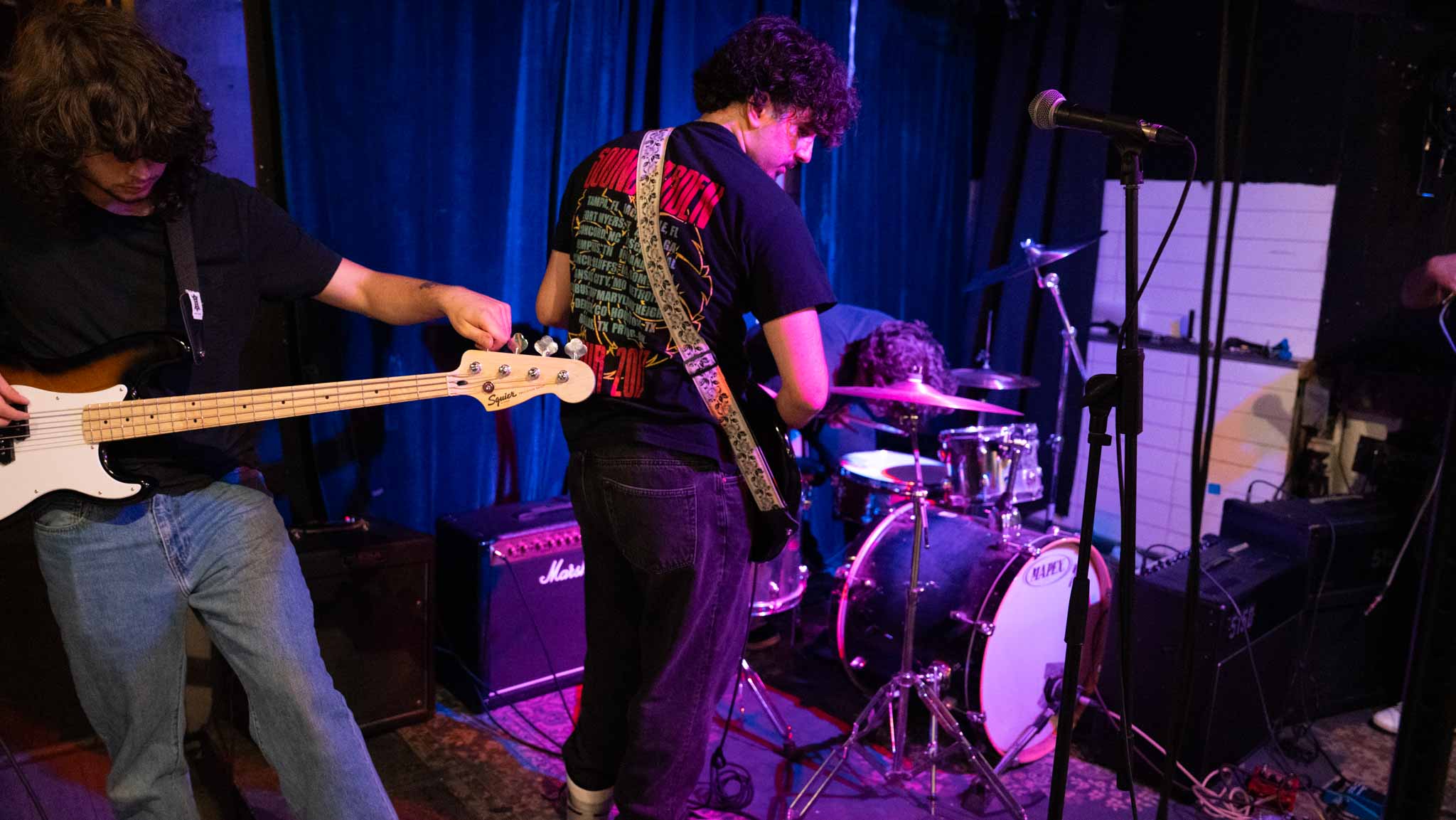 The band gathered around a drum kit on a small stage