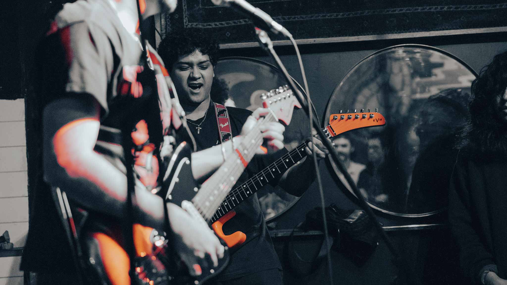 Guitarist playing mid-set in a red, black, and white photograph