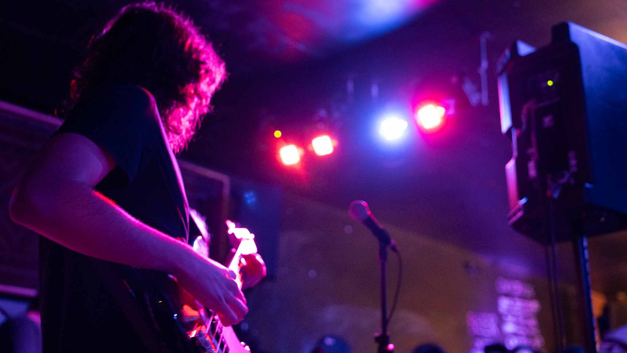 Guitarist silhouetted beneath red and blue stage lights